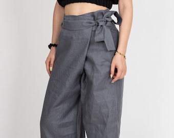 May include: Gray linen pants with a wide leg and a wrap-style waistband that ties at the front with a bow. The pants have a relaxed fit.