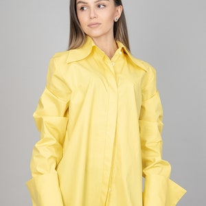 May include: An oversized yellow button-down shirt with a large collar and long sleeves. The shirt has a relaxed fit and features a button closure.