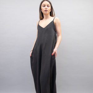 May include: A black sleeveless maxi dress with a V-neckline. The dress is made of a soft, flowing fabric and has a relaxed fit.
