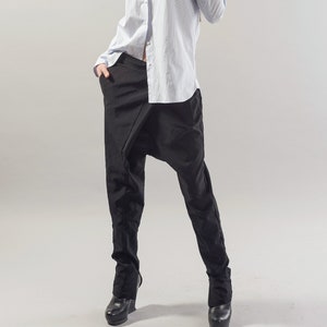 May include: A woman wearing a light blue striped button-down shirt with a pearl necklace and black pants. She is wearing black sunglasses and has her hair pulled back.