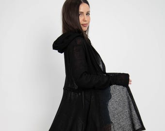 May include: A black hooded cardigan with a long, asymmetrical hemline. The cardigan is made of a lightweight, knit fabric and has a drawstring waist.