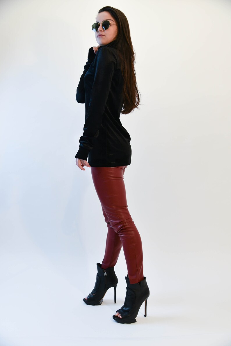 May include: A woman wearing a black turtleneck sweater and burgundy leather pants. She is wearing black heeled boots with a peep toe.
