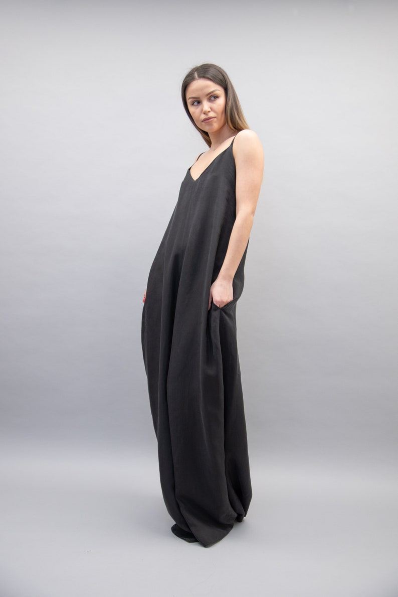 May include: A black sleeveless maxi dress with a loose, flowing fit. The dress has a simple, elegant design and is made from a soft, comfortable fabric.