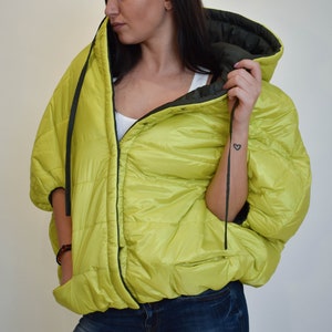 May include: A lime green puffer jacket with a black zipper and a black drawstring hood. The jacket has a quilted design and a relaxed fit.