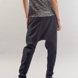 May include: Black trousers with a loose, baggy fit and a gathered detail at the ankles. The trousers are made of a lightweight fabric and have a relaxed, comfortable feel.
