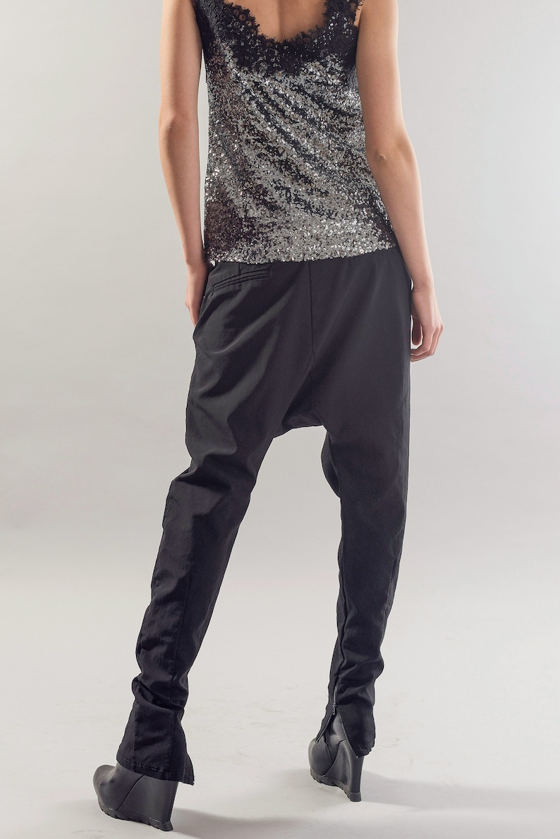 May include: Black trousers with a loose, baggy fit and a gathered detail at the ankles. The trousers are made of a lightweight fabric and have a relaxed, comfortable feel.