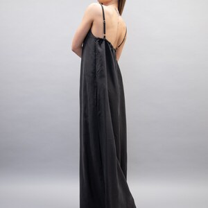 May include: A black maxi dress with thin straps. The dress has a loose, flowing fit and a gathered neckline.