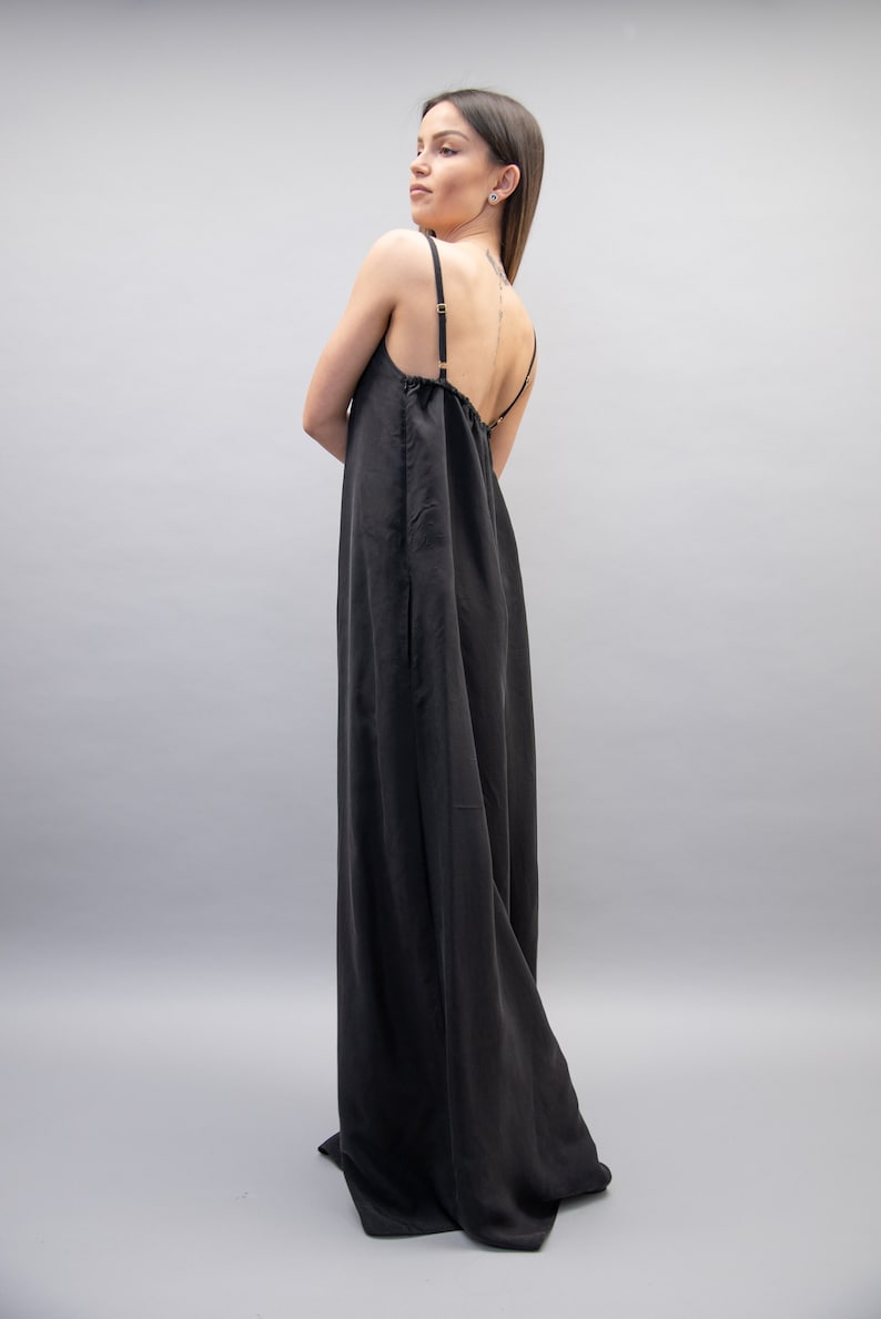 May include: A black maxi dress with thin straps. The dress has a loose, flowing fit and a gathered neckline.