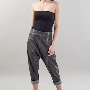 May include: A woman wearing a black strapless top, gray leather pants with a zipper detail, and black heeled sandals. She is wearing a black headband.