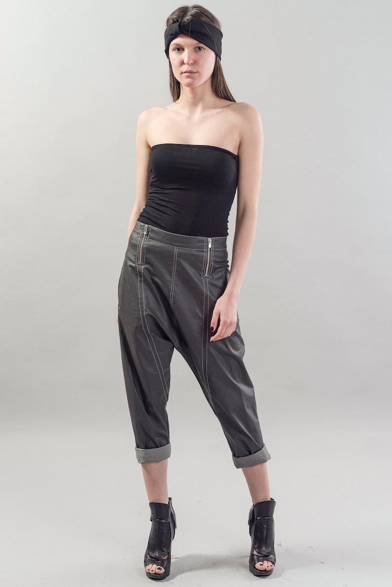 May include: A woman wearing a black strapless top, gray leather pants with a zipper detail, and black heeled sandals. She is wearing a black headband.