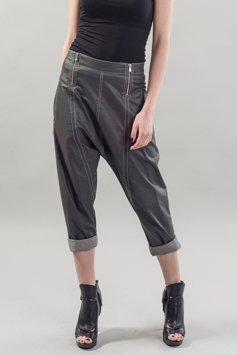 May include: Gray leather pants with a cuffed hem and zipper detailing. The pants have a loose fit and are styled with black heeled ankle boots.