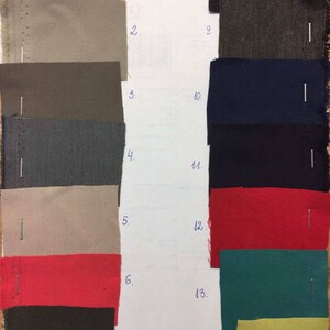 May include: A fabric swatch card with 14 different fabric samples. The samples are arranged in two columns, with numbers 1 through 7 on the left and 8 through 14 on the right. The fabrics are in a variety of colors and textures, including beige, gray, black, red, green, and yellow.
