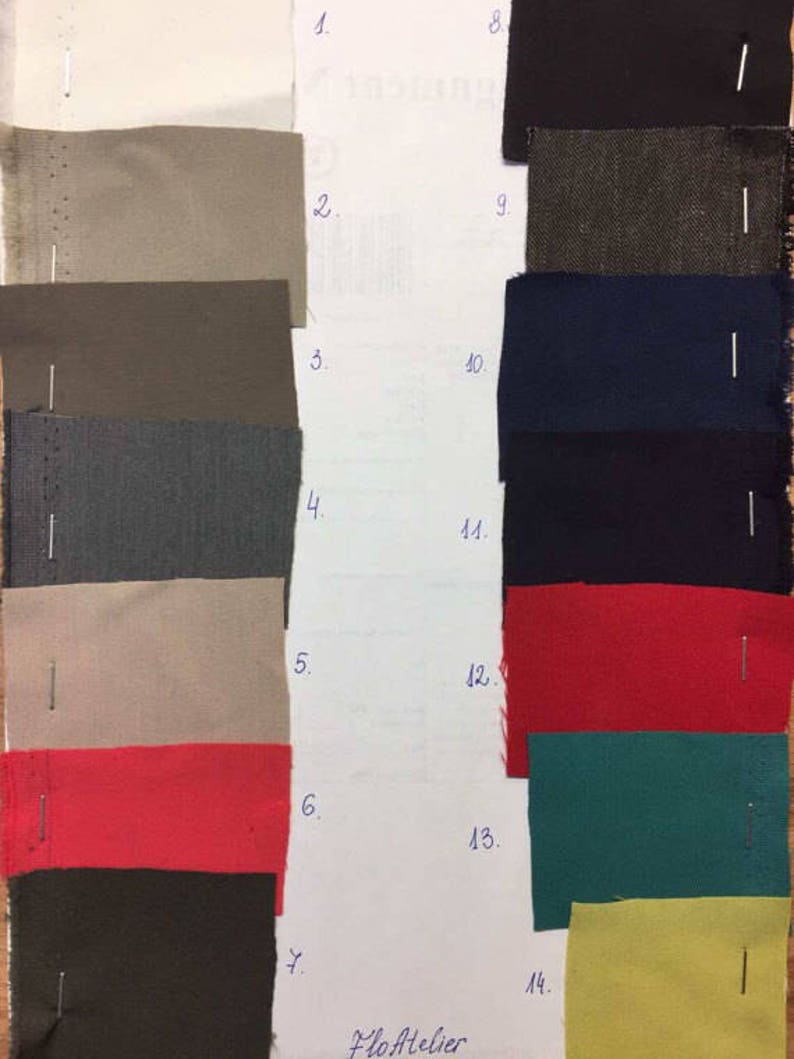 May include: A fabric swatch card with 14 different fabric samples. The samples are arranged in two columns, with numbers 1 through 7 on the left and 8 through 14 on the right. The fabrics are in a variety of colors and textures, including beige, gray, black, red, green, and yellow.