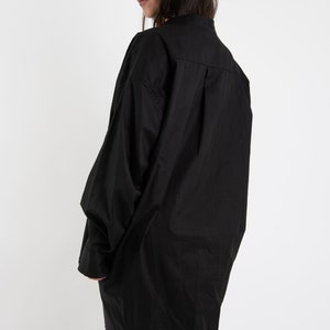 Puede incluir: Una camisa negra de gran tama&ntilde;o con cuello y mangas largas. La camisa est&aacute; hecha de una tela suave y ligera y tiene un corte holgado.
