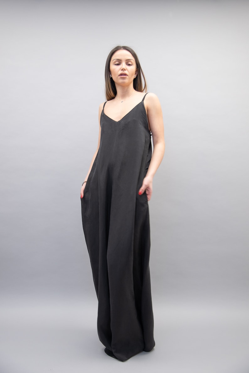 May include: A black sleeveless maxi dress with a V-neckline. The dress is made of a soft, flowing fabric and has a relaxed fit.