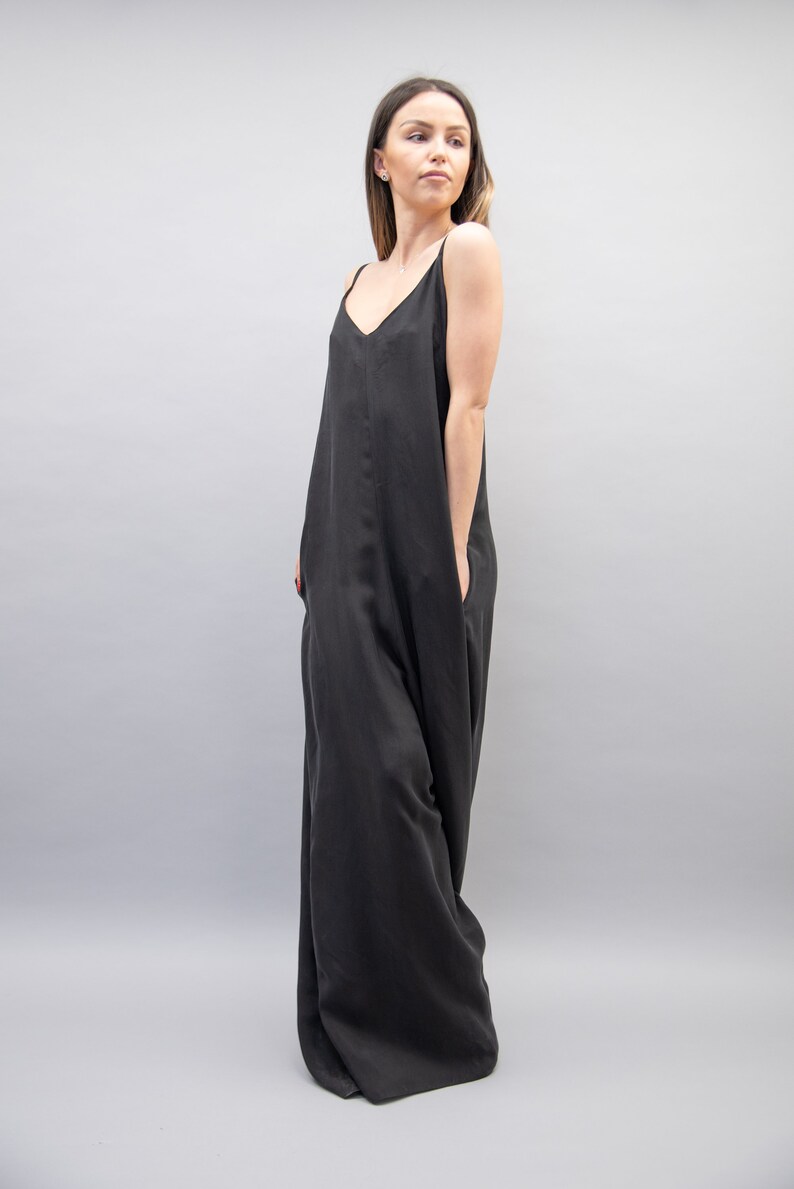 May include: A black sleeveless maxi dress with a V-neckline. The dress has a relaxed fit and is made of a soft, flowing fabric.