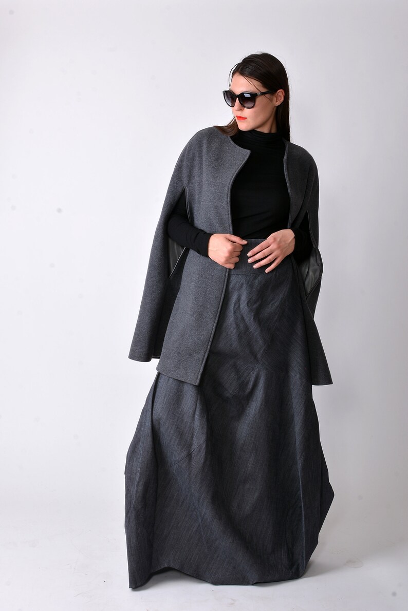 May include: A gray cape with a black turtleneck and a gray pinstripe skirt. The cape has a zipper closure and a collar.
