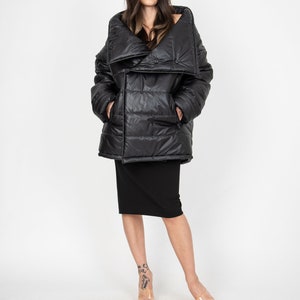 May include: A black puffer jacket with a large, folded collar. The jacket has a quilted design and a button closure.