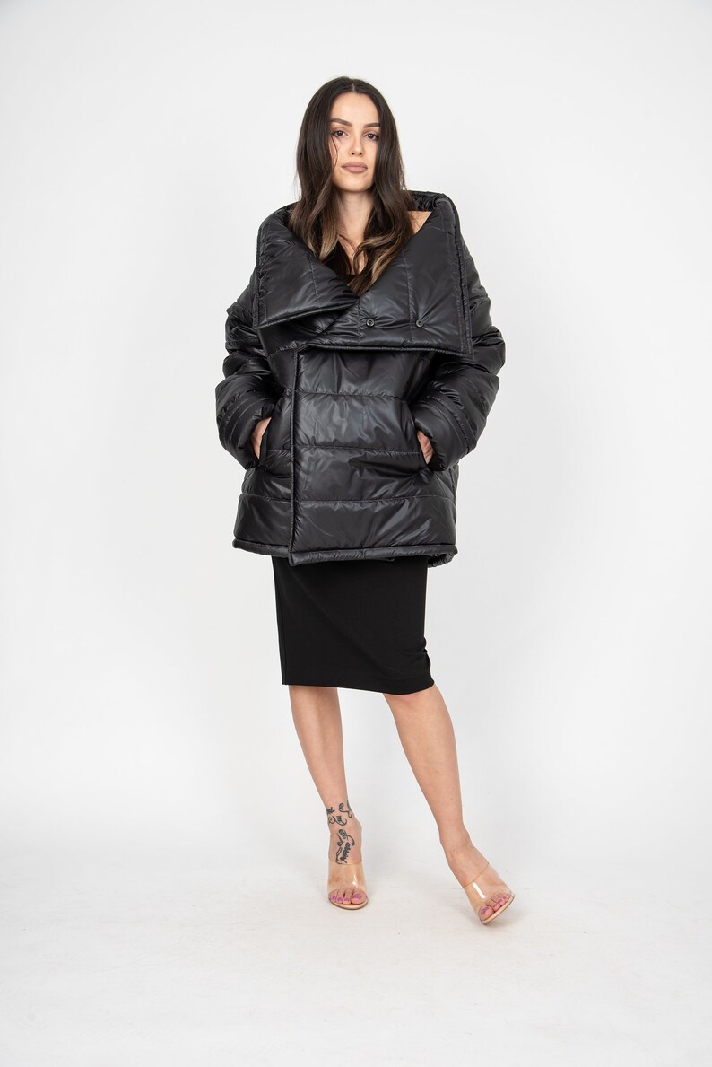 May include: A black puffer jacket with a large, folded collar. The jacket has a quilted design and a button closure.