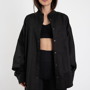 Puede incluir: Una camisa negra de gran tama&ntilde;o con cuello mandar&iacute;n y cierre de botones. La camisa est&aacute; hecha de una tela suave y ligera y tiene un corte holgado.