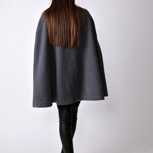 May include: A gray cape with a long, straight hemline. The cape is made of a soft, comfortable fabric and is perfect for layering over a variety of outfits.