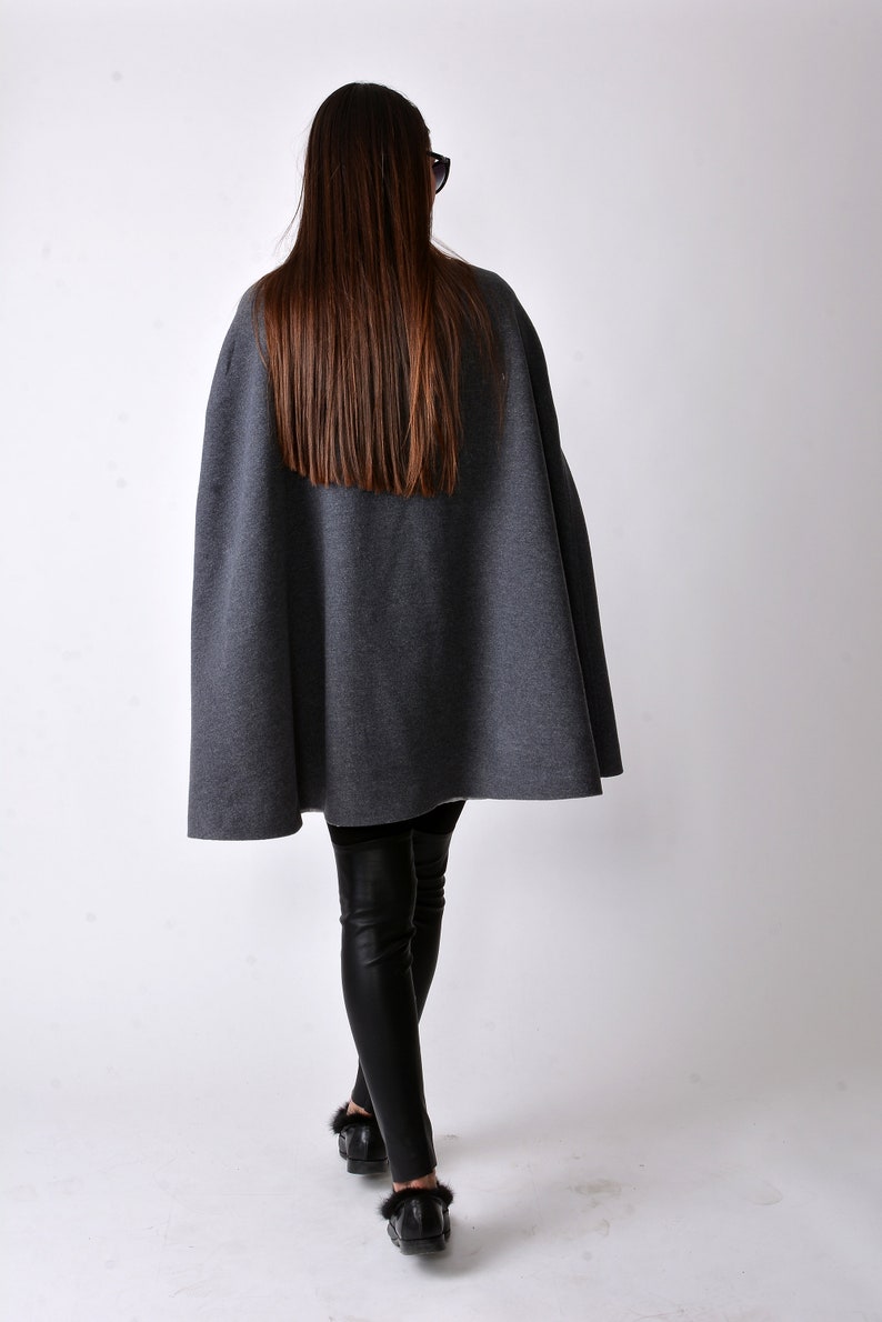 May include: A gray cape with a long, straight hemline. The cape is made of a soft, comfortable fabric and is perfect for layering over a variety of outfits.