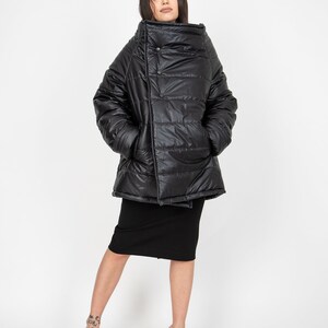 May include: A black puffer jacket with a high collar and a single button closure. The jacket is made of a shiny, quilted fabric and has a relaxed fit.