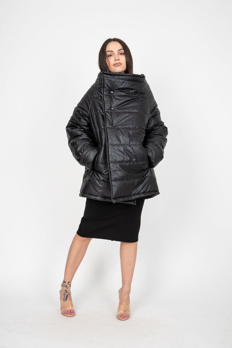 May include: A black puffer jacket with a high collar and a single button closure. The jacket is made of a shiny, quilted fabric and has a relaxed fit.