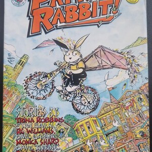 May include: Comic book cover titled "Patrick Rabbit!" featuring a rabbit riding a bicycle with wings over a city. The cover art is colorful with text that reads "Stories By" and the names of the authors.