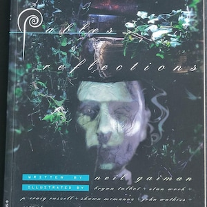 May include: A comic book cover for "The Sandman: Fables & Reflections" by Neil Gaiman. The cover features a surreal image of a face with a blurred effect, surrounded by greenery and stacked books. The title and author's name are prominently displayed.