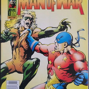 May include: Comic book cover featuring two superheroes in a fight. The superhero on the left is wearing a green and orange costume with a mask. The superhero on the right is wearing a red and blue costume with a mask and a cape. The title of the comic is "Man of War" with the words "Tom Mason & Dan Danko" above the title.