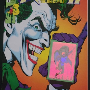 Könnte beinhalten: Comic-Cover für Robin II: The Joker's Wild! mit einer Nahaufnahme des Jokers, der eine Karte mit Robin darauf hält. Das Cover hat ein lebendiges Farbschema mit dem DC Comics-Logo.