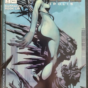 Puede incluir: Una portada de cómic con una mujer de piel azul con cabello negro largo de pie sobre un afloramiento rocoso. El título "DARK MINDS: MACROPOLIS vol.2" está impreso en blanco sobre fondo negro. El texto "CHAPTER 1: "Another Night on the Town" está impreso en blanco sobre fondo negro.