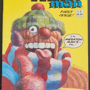 Może przedstawiać: Okładka komiksu "Yarn Man" autorstwa Dona Simpsona. Okładka przedstawia kolorową, kreskówkową postać z dużymi ustami i zielonym kapeluszem. Tekst zawiera "First Issue!" i "No. 1".