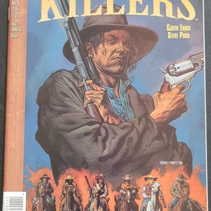 May include: Comic book cover for "Saint of Killers" featuring a man in a hat holding a rifle and a revolver. The cover art has a Western theme with a group of riders on horseback at the bottom. The DC Vertigo comic is issue No. 1 of 4.