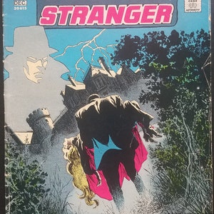 May include: A comic book cover featuring a shadowy figure in a cape and hat, with the title "The Phantom Stranger" and the words "Phantom DC Stranger" in a red and white logo. The cover also features a dark castle and a lightning bolt.