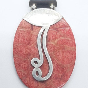 May include: A silver pendant with a pink coral stone and a silver swirl design.