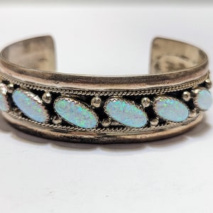 May include: A silver bracelet with a row of oval-shaped opal stones set in a silver band.
