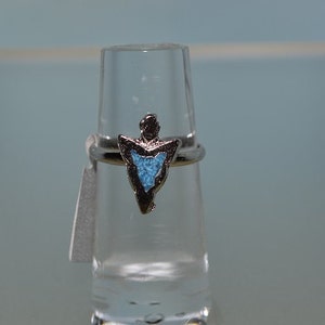 Op de afbeelding: Een zilveren ring met een turquoise pijlpuntontwerp.