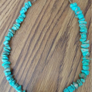 Peut inclure: Un collier turquoise composé de pierres de forme irrégulière. Le collier est enfilée sur une chaîne en argent.