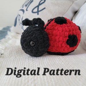 May include: A crocheted ladybug plush toy with black and red yarn. The ladybug has black spots and a black head with a single black eye. The toy is lying on a white surface with the text "Digital Pattern" below it.