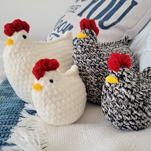 May include: Four crocheted chicken plushies. Two are white with red combs and yellow beaks. Two are black and white with red combs and yellow beaks.