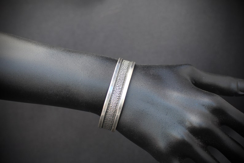 Rustic Silver Styling 3153 Sterling Silver Cuff with a Textured Center on a Black Background With a Smooth Silver Border in Southwestern