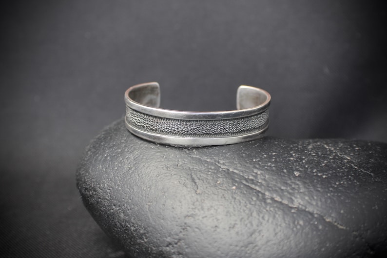 Rustic Silver Styling 3153 Sterling Silver Cuff with a Textured Center on a Black Background With a Smooth Silver Border in Southwestern