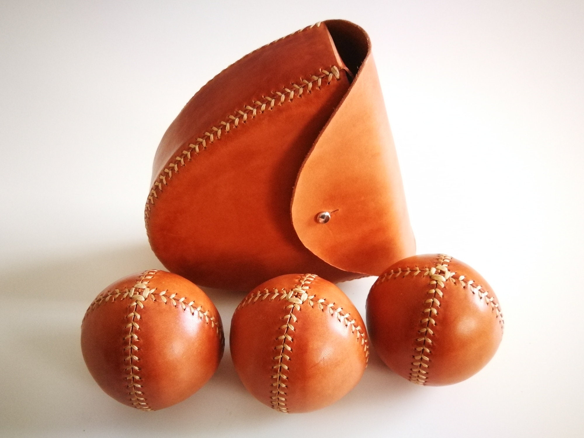 Set of three handmade juggling balls in natural leather with belt case, 45 to 75mm, stitched with baseball stitch. Perfect gift for jugglers