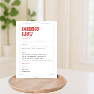 Puede incluir: Una tarjeta blanca con una lista de bebidas impresa en rojo y gris. La lista incluye nuestras bebidas favoritas, aperitivos, vinos y opciones sin alcohol.