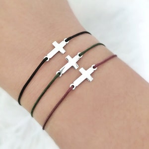 May include: Three bracelets with silver cross charms on black, green, and burgundy cords.