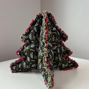 May include: A black and green fabric Christmas tree with red and green trim. The tree is decorated with a white leaf and berry pattern.