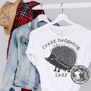 May include: White t-shirt with a black and white illustration of a hedgehog and the text "crazy hedgehog lady".