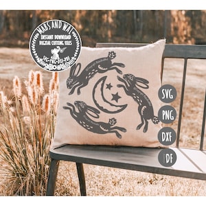 Puede incluir: Un cojín beige con un diseño gris oscuro de tres conejos, una luna creciente y estrellas. El cojín está sobre un banco de metal oscuro. La imagen también incluye el texto "MABS AND WAL" e iconos de tipo de archivo: SVG, PNG, DXF y PDF.